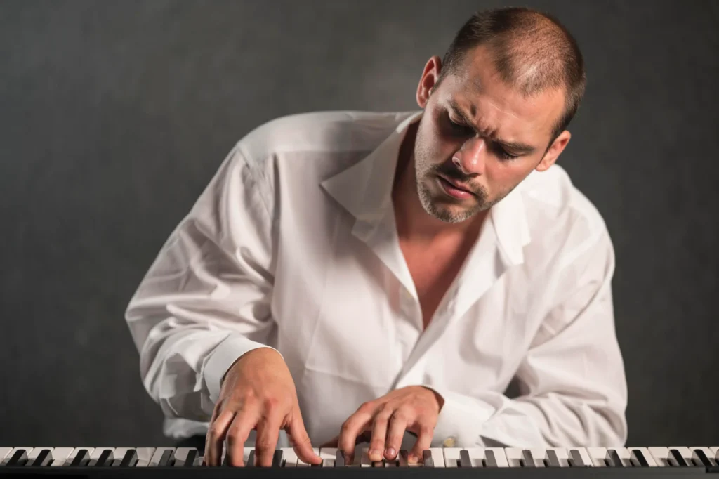 Man in white shirt playing keyboard.